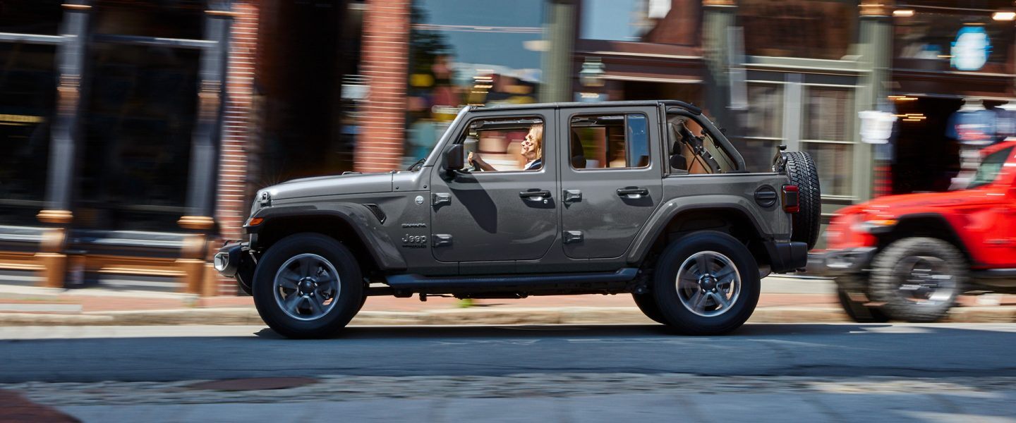 A 2021 Jeep Wrangler Sahara being driven on a busy city street.